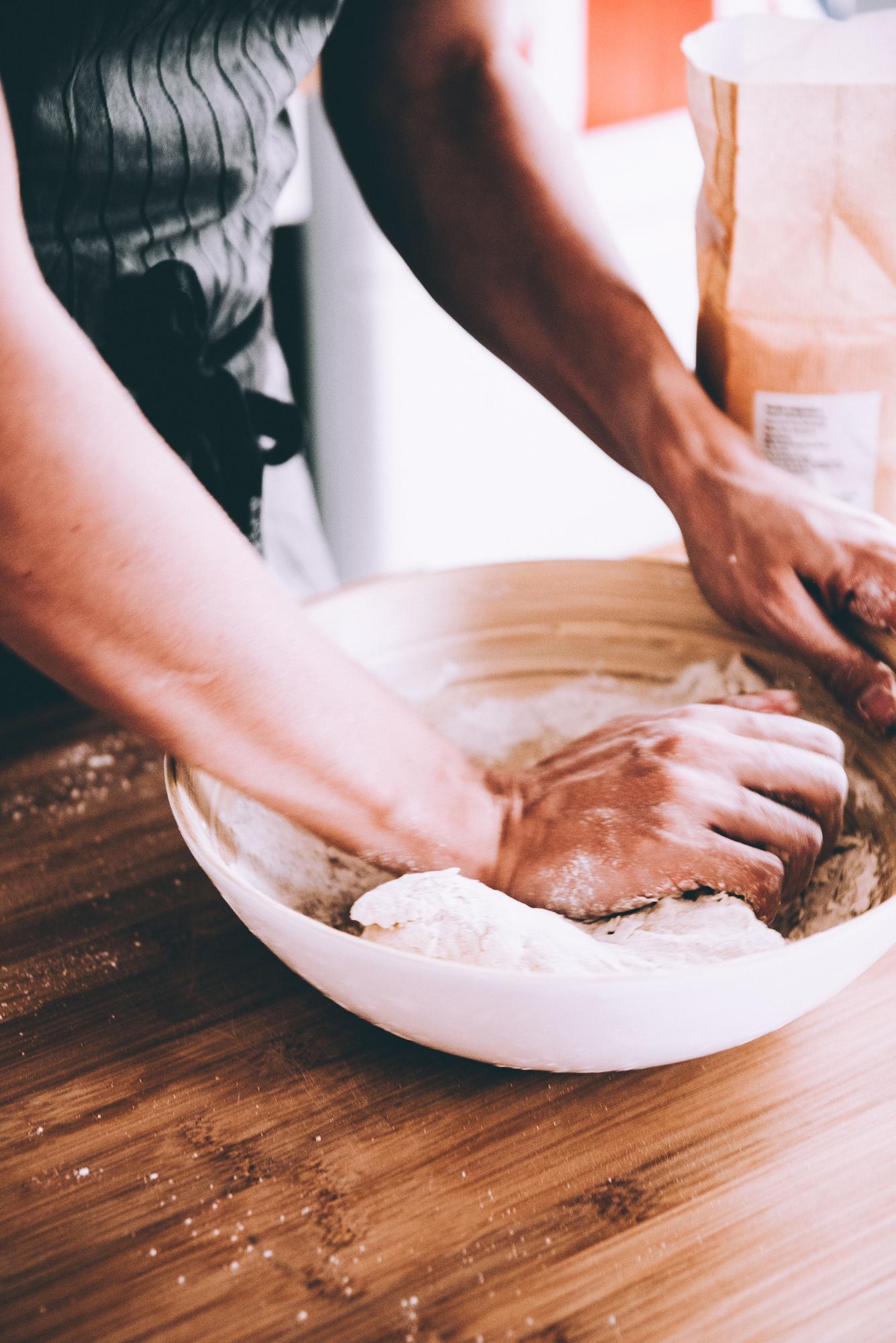 Dettaglio mani che preparano impasto in cucina professionale
